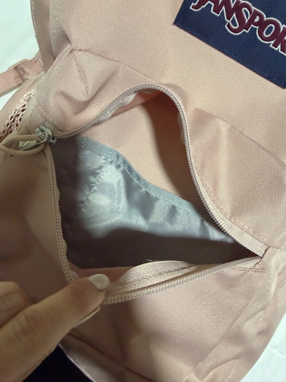 JanSport Cross Town backpack in a light pink color with a blue logo patch